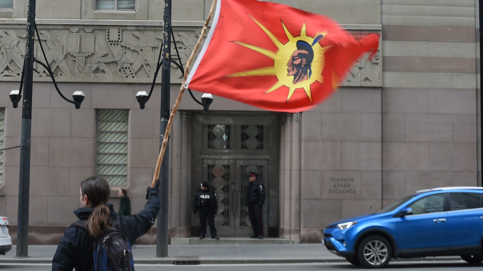 A man waves the Mohawk Warrior Society flag at a protest outside TD Bank's headquarters in downtown Toronto on March 30, 2017, to demand that the company end its partnership with Kinder Morgan. Photo by National Observer.