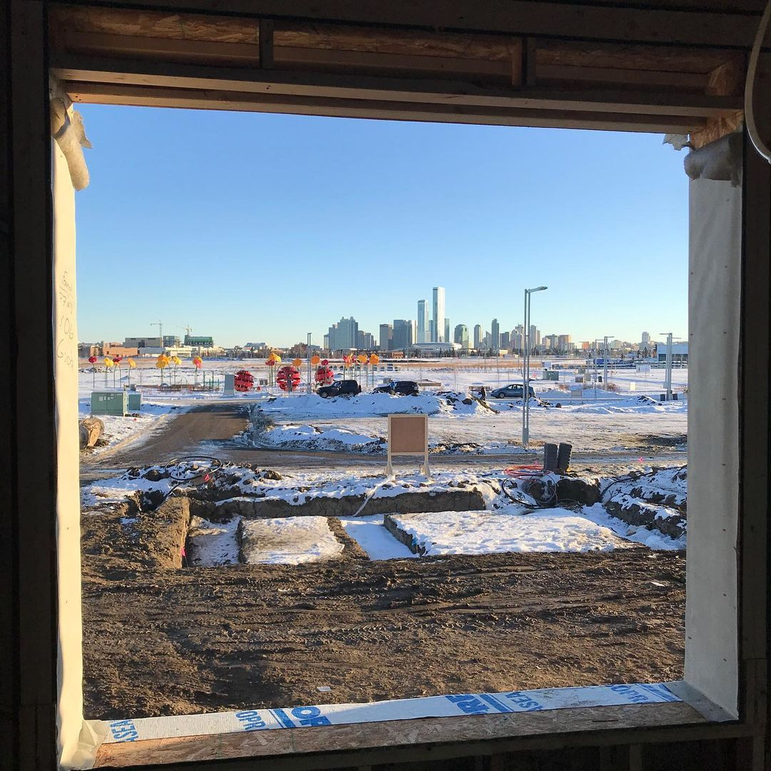 A construction site covered in snow, with a city skyline in the background