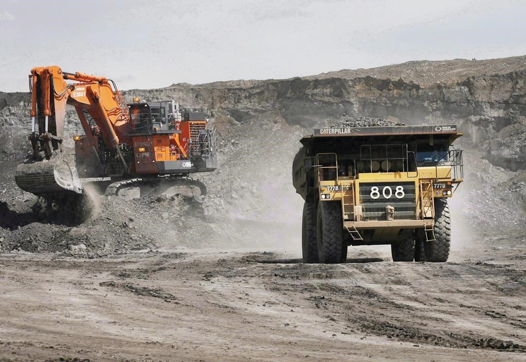 A haul truck carrying a full load drives away from a mining shovel at the Shell Albian Sands oilsands mine near Fort McMurray, Alta., on Monday.July 9, 2008
