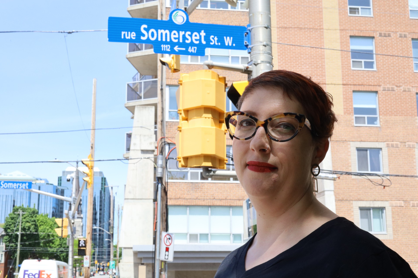 Headshot of a woman standing with a street sign that says 