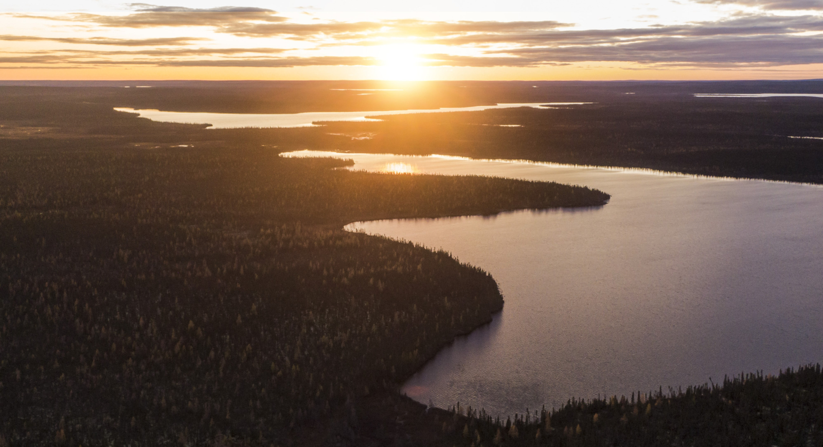 The sun sets over the Seal River Watershed in Northern Manitoba. The network of rivers is lit up by the sun.