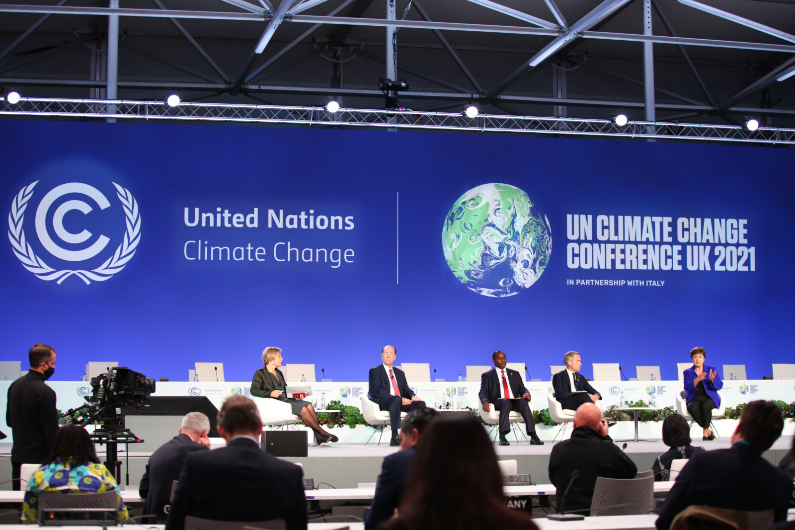 Five people sit on a stage at COP26 in Glasgow, with a blue background that reads United Nations Climate Change behind them
