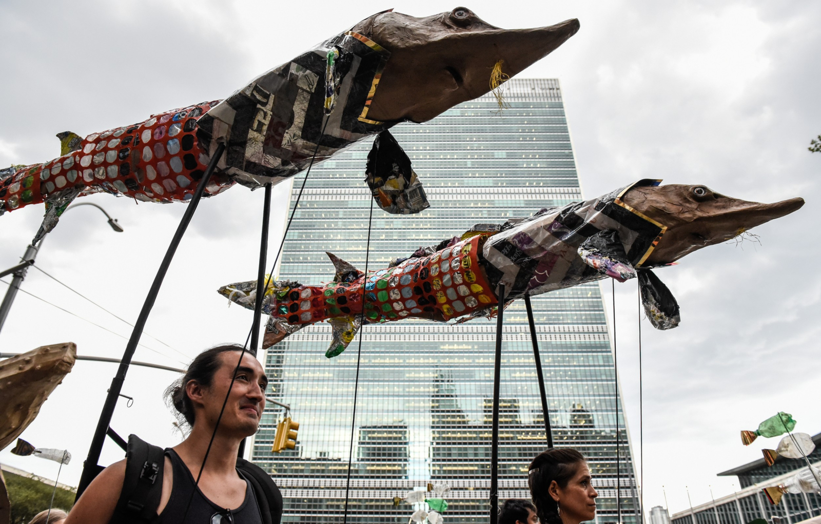 people march holding large paper mache fish sculptures