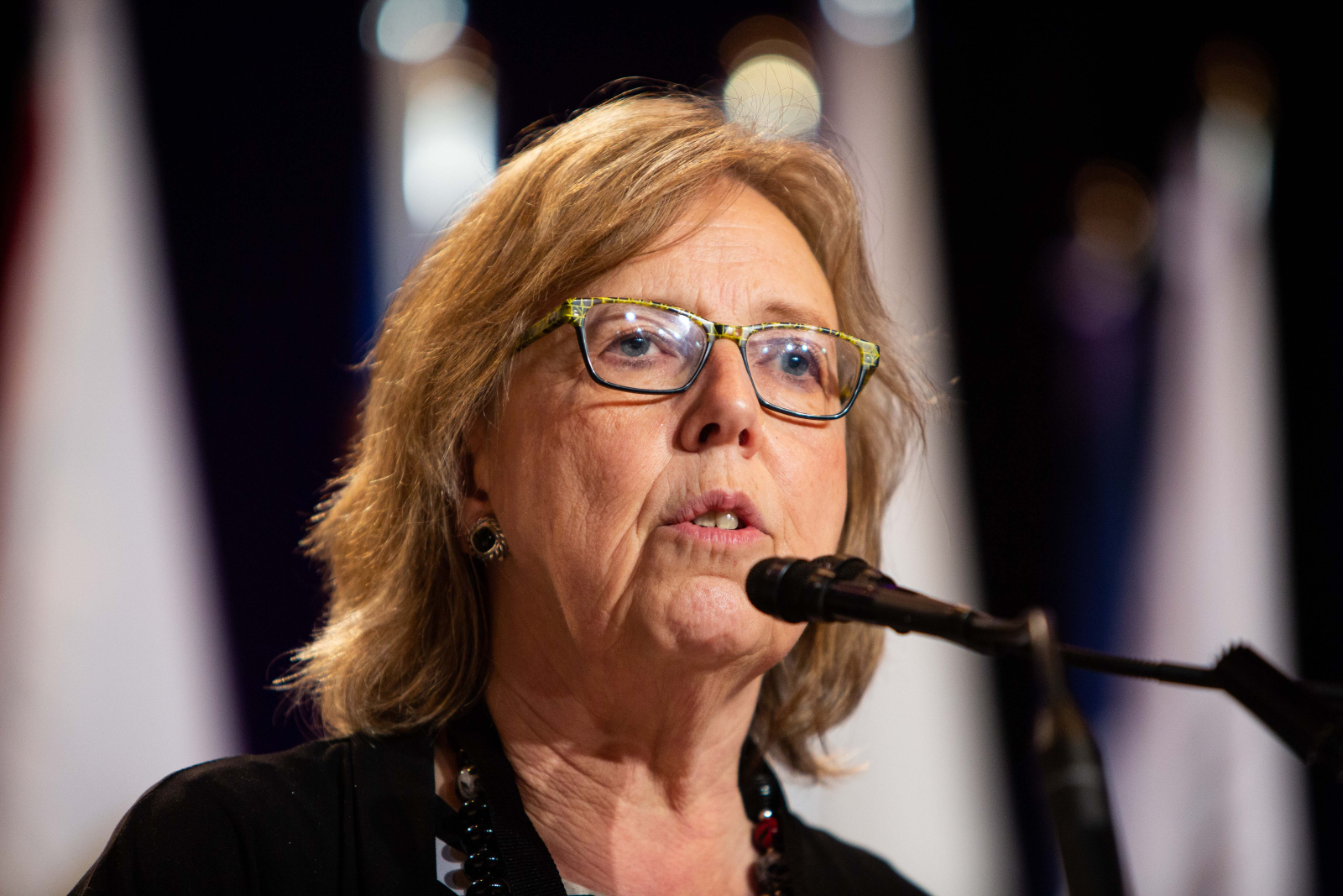 close up of a woman wearing glasses speaking into a microphone