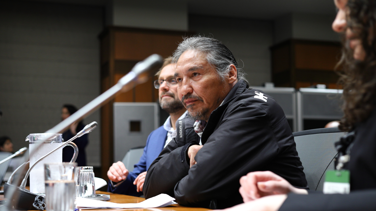 ACFN Chief Allan Adam sits at a table in the House of Commons committee room, waiting for the meeting to start.