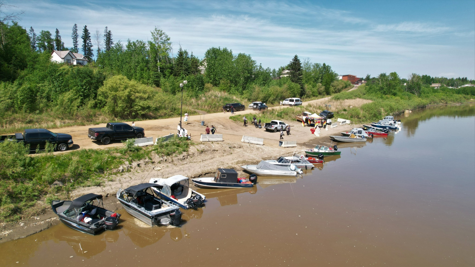 Boats and trucks line the shore of a river