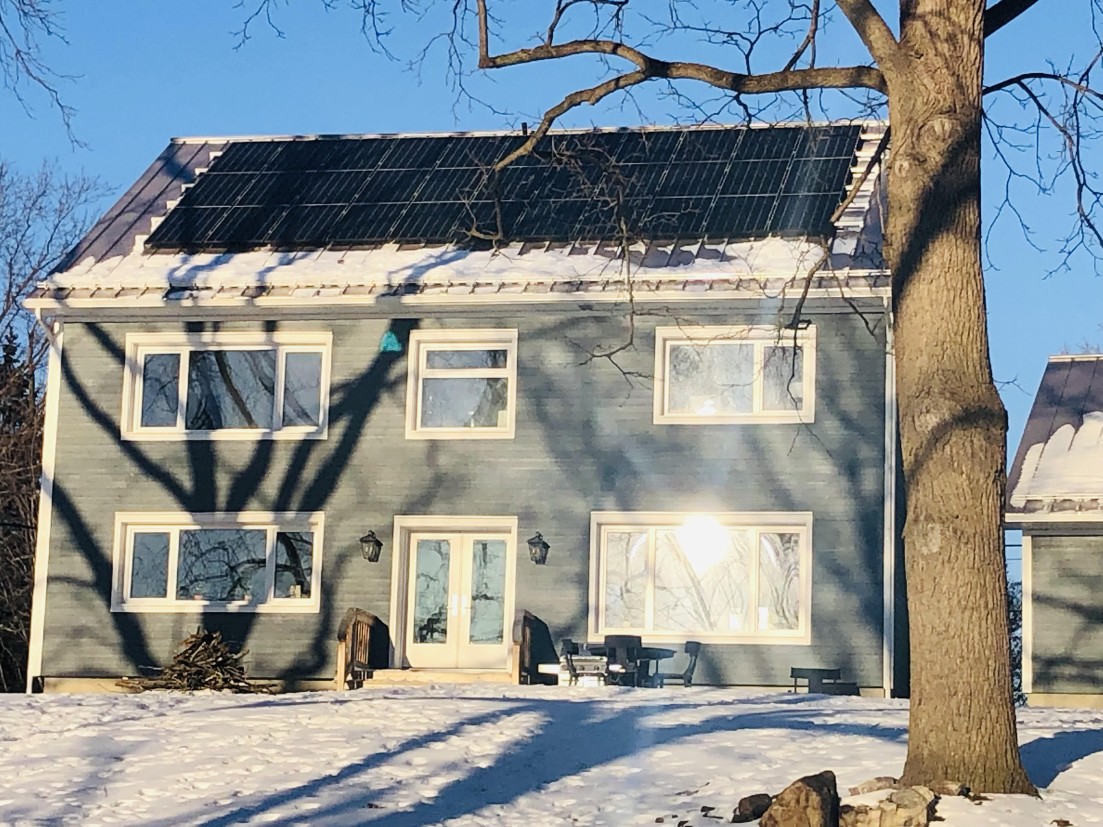 A blue house with solar panels on the roof on a sunny winter day