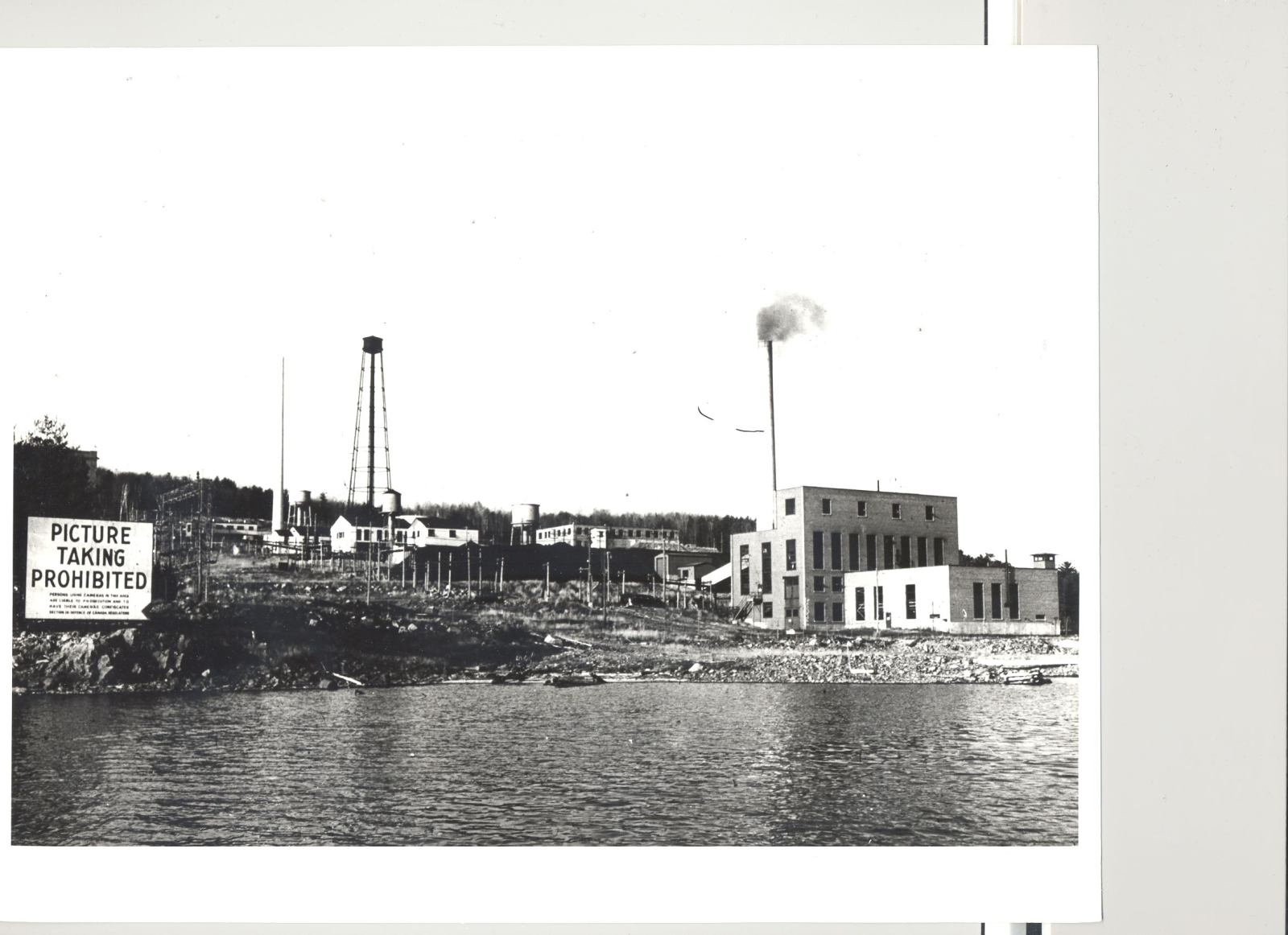 Chalk River Labs photographed from the Ottawa River in the late 1940s. Includes a sign on the shore saying 
