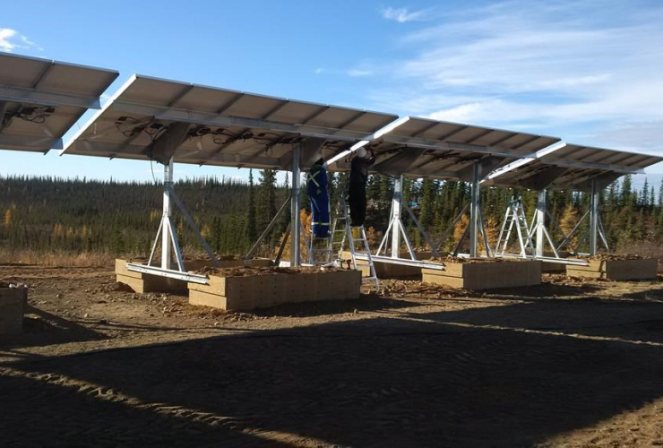 Workers attend to a solar array in the town of Colville Lake. Photo: Canadian Press