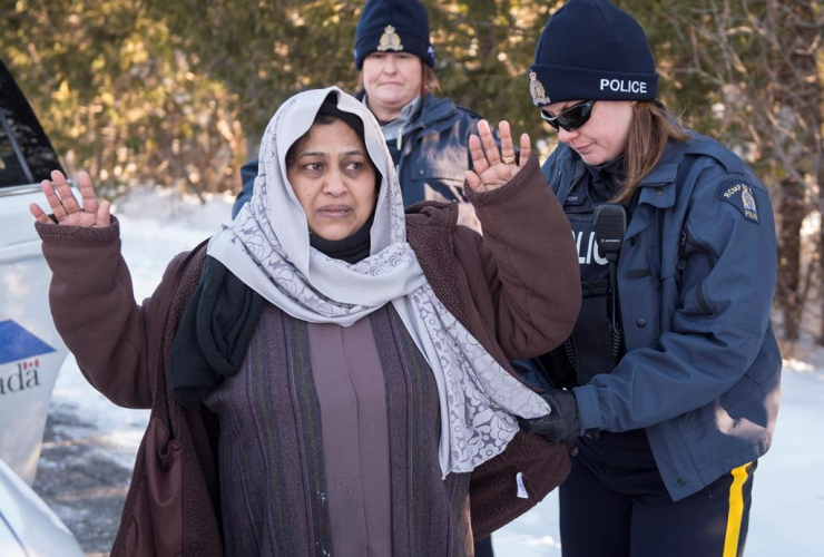 An RCMP officer frisks as asylum claimant after crossing the border into Canada from the United States with her two daughters,  Friday, March 17, 2017 near Hemmingford,