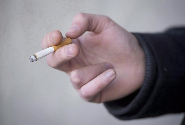 A smoker holds a cigarette during a smoke break outside a building in North Vancouver, B.C. Monday, Jan. 20, 2014.