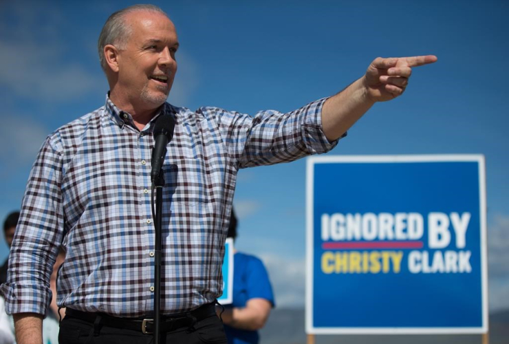NDP Leader John Horgan gestures while standing in front of a sign reading "Ignored By Christy Clark" during a healthcare related campaign stop in Kamloops, B.C., on Tuesday May 2, 2017.