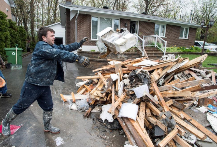David Samuelson throws debris from his flooded house onto a pile on his driveway in the Pierrefonds borough of Montreal Sunday, May 14, 2017.