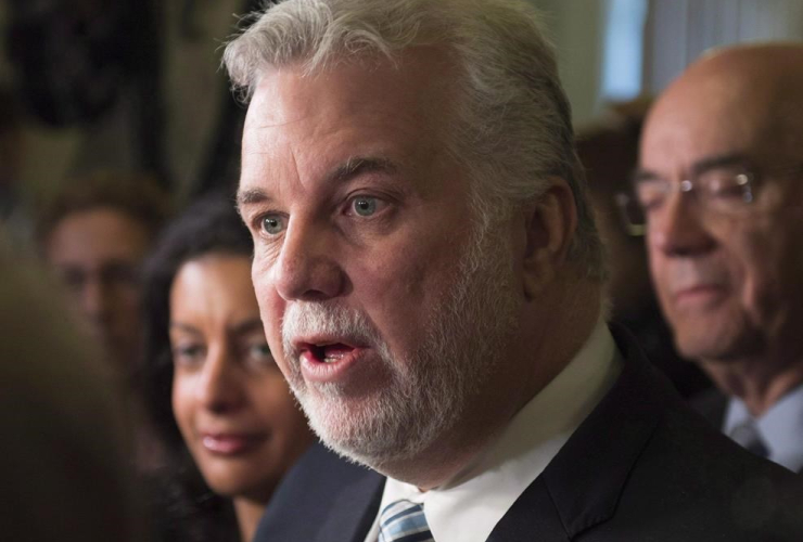 Quebec Premier Philippe Couillard, centre, speaks to reporters at a news conference to comment the Bombardier C-Series deal with Delta Airlines on Thursday, April 28, 2016 at the legislature in Quebec City.