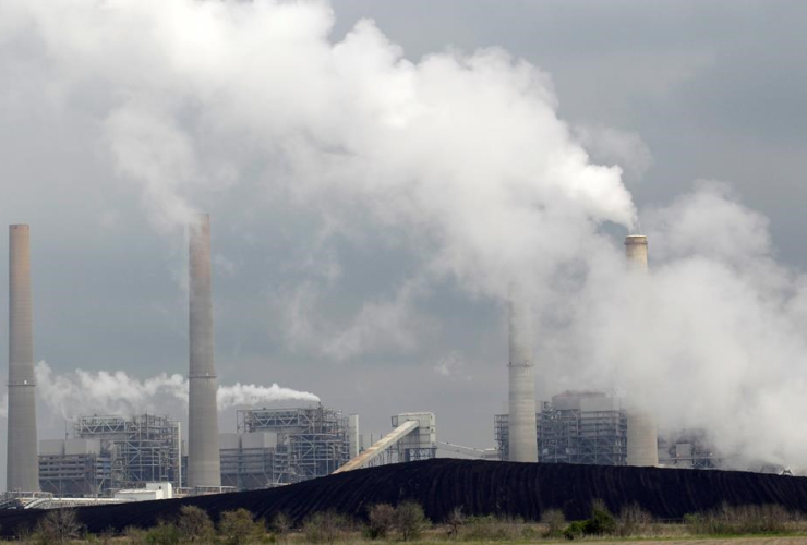 In this March 16, 2011 file photo, exhaust rises from smokestacks in front of piles of coal at NRG Energy's W.A. Parish Electric Generating Station in Thompsons, Texas.
