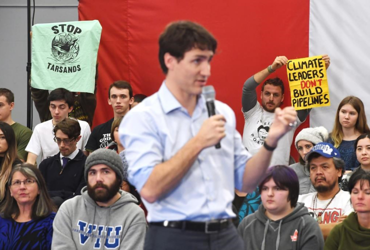 A member of the audience holds up a sign reading "Climate leaders don't build pipelines" as Prime Minister Justin Trudeau speaks in Nanaimo, B.C.