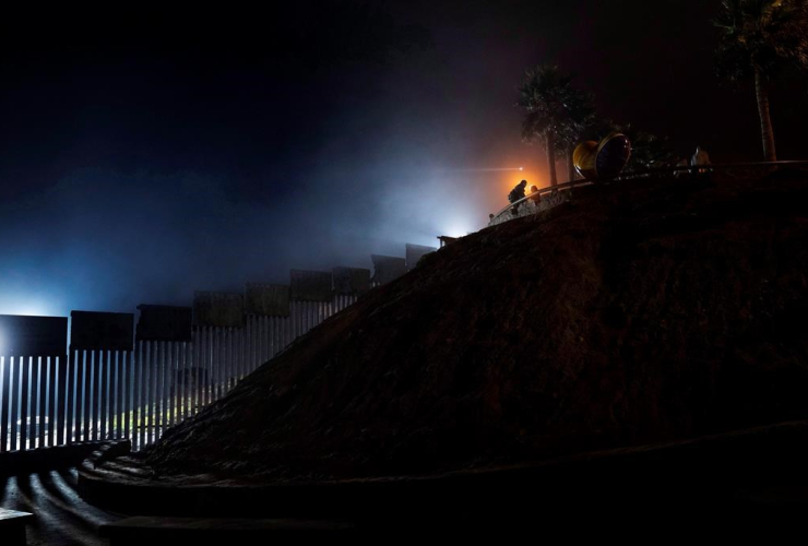 couple, street lamp, U.S. border wall, Tijuana, Mexico, 