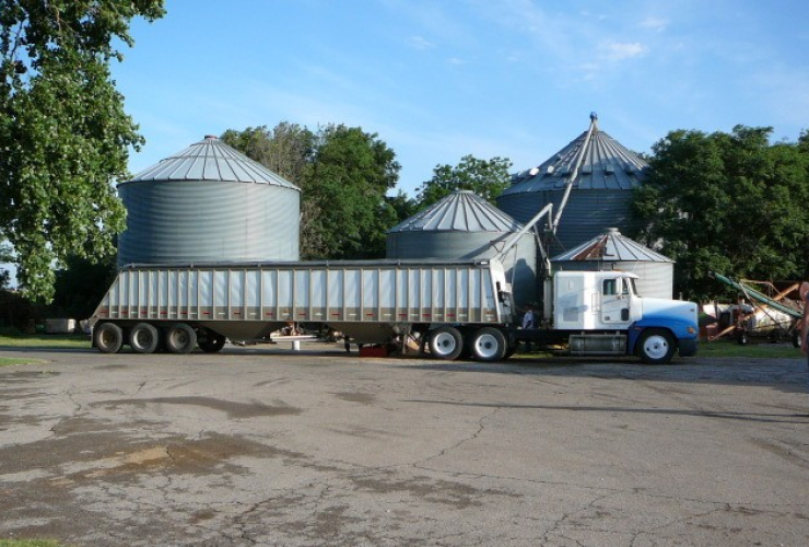 A truck unloads grain into a grain dryer at a farm
