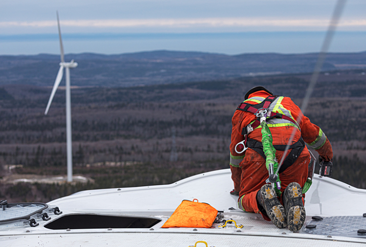 a worker in high vis, on top of a wind turbine in quebec